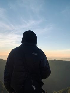 a person standing on top of a hill looking at the sky and mountains in the distance