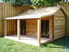 a dog house built into the side of a fenced in area with grass and trees