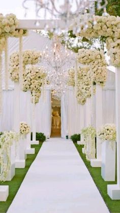 an outdoor ceremony with white flowers and chandeliers