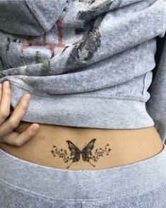 a woman's stomach with a butterfly tattoo on her left side ribcage