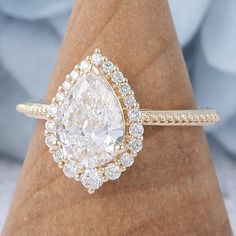 a pear shaped diamond ring on top of a wooden stand