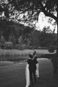 a man and woman standing in front of a lake