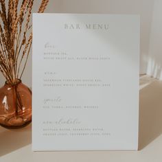 a menu card sitting on top of a table next to a vase