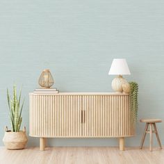 an empty room with a wooden cabinet next to a lamp and a potted plant