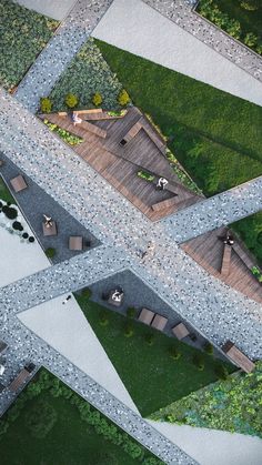 an aerial view of people sitting on benches in the middle of a park with grass and trees