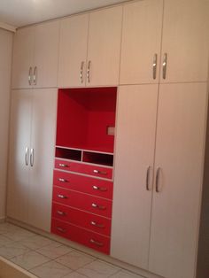 an empty room with white cabinets and red drawers