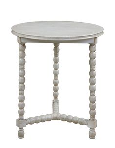 a white table with beaded legs and a small round top on the bottom shelf