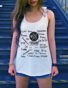 a woman standing in front of some stairs wearing a white tank top with the word sos on it