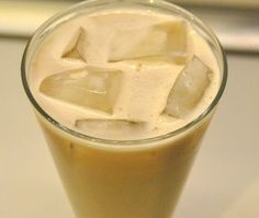 a drink with ice cubes in it sitting on top of a white countertop