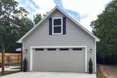 a gray house with black shutters on the front door and windows in the garage