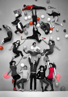 a group of people standing in front of a wall with balloons and balls on it