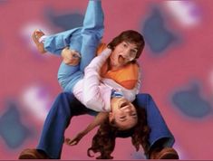 two people in the air with their arms around each other and one person holding another