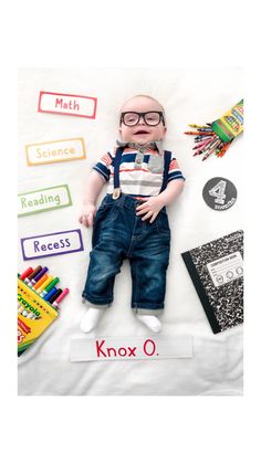 a baby doll laying on top of a white sheet next to books and pencils