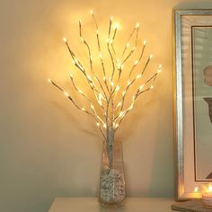 a vase with some lights in it next to a painting and a framed picture on the wall