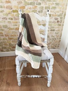 a white chair with a blanket on top of it in front of a brick wall