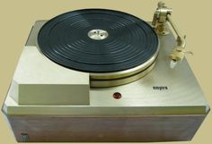 an old record player sitting on top of a white sheet covered table with gold trim