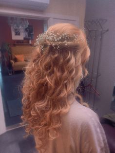 the back of a woman's head with long curly hair and a crown of flowers