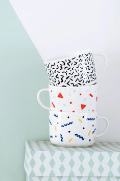 three cups are stacked on top of each other and one is painted with colorful shapes