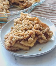 a piece of pie sitting on top of a white plate next to a glass dish