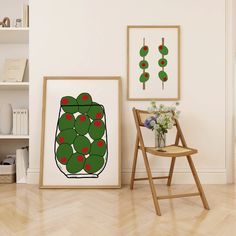 a chair sitting in front of two pictures on the wall next to a wooden floor