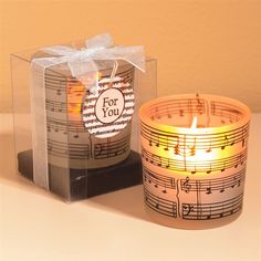 a candle that is sitting next to a box with music notes on it and the words for you