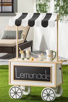 a lemonade cart sitting on top of a lush green field next to a building