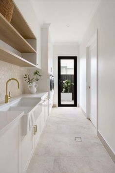 a long narrow hallway with white cabinets and open shelving above the kitchen sink area