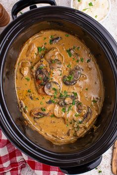 a crock pot filled with mushroom stew and garnished with parsley