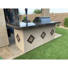 an outdoor kitchen with black granite counter tops and tile backsplashes on the outside