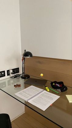 a glass desk with a notepad, pen and ball sitting on top of it