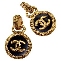 Introducing the exquisite Chanel 1993 Gold Tone Black CC Medallion Florentine Earrings, a stunning pair that exudes timeless elegance and sophistication. Crafted with meticulous attention to detail, these earrings are sure to elevate any ensemble with their unique design and impeccable craftsmanship. The earrings feature textured gold-plated discs adorned with black enamel charms, each embellished with a striking gold-plated CC logo at its center. This iconic Chanel motif adds a touch of luxury and glamour to the design, making these earrings a true statement piece. With their clip-on style, these earrings are both comfortable to wear and easy to style. The textured gold finish adds a unique and eye-catching touch that sets them apart from the rest of your collection, ensuring you stand ou Luxury Chic Black Enamel Jewelry, Luxury Polished Clip-on Earrings For Formal Occasions, Luxury Clip-on Earrings For Formal Occasions, Luxury Clip-on Earrings For Anniversary, Luxury Polished Clip-on Earrings For Anniversary, Luxury Hallmarked Clip-on Earrings For Anniversary, Luxury Gold Clip-on Earrings, Luxury Drop Clip-on Earrings For Formal Occasions, Luxury Hallmarked Earrings For Evening