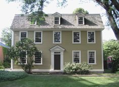 a brown house with white trim and windows on the top floor is surrounded by green grass