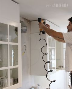 a man is painting the walls in his kitchen with white paint and black electrical wires