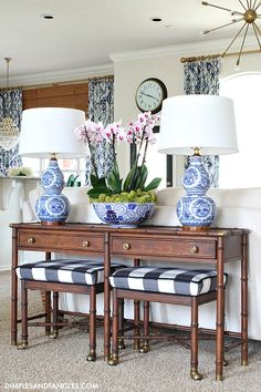 a table with two blue and white vases sitting on top of it next to lamps