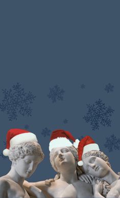 three statues wearing santa hats against a blue background