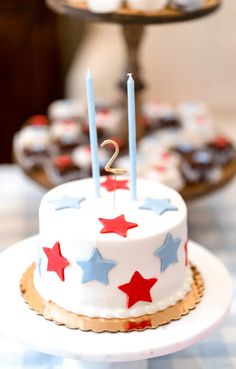 a white cake with red and blue stars on it sitting on top of a table