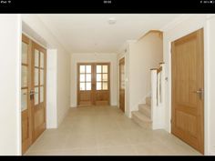 an empty hallway with two wooden doors and some steps leading up to the second floor