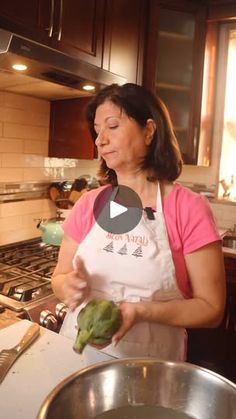 a woman standing in a kitchen preparing food on top of a metal pan filled with green peppers