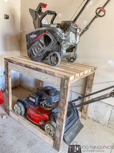 two lawn mowers are sitting on top of a wooden crate in a garage