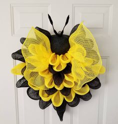 a yellow and black mesh sunflower wreath hanging on a door