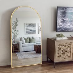 a living room with a couch, mirror and painting on the wall next to it