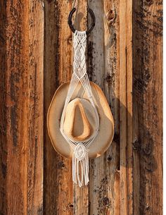 a hat hanging on the side of a wooden wall with a rope attached to it