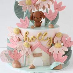 a cake decorated with flowers and a dog sitting on top of the frosted cake