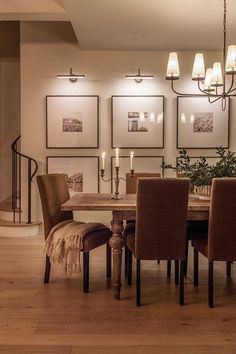 a dining room table and chairs with pictures on the wall behind them in an elegant setting