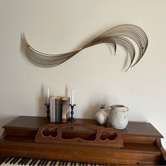 a vase and some books on a table with a piano in front of the wall