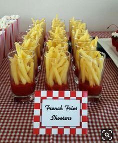 french fries are arranged in glasses on a table with red and white checkered cloth