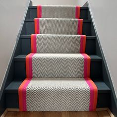 the carpeted stairs are decorated with pink and grey chevrons, along with matching rugs