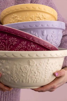 a woman is holding four bowls in her hands, each with different designs on them