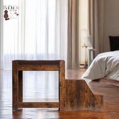 a wooden table sitting on top of a hard wood floor next to a white bed