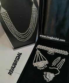 an open box with two necklaces and earrings in it on a table next to a black case